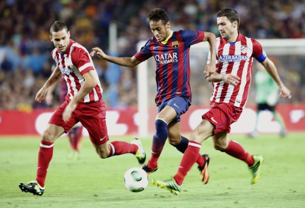 Neymar running between two Atletico Madrid defenders