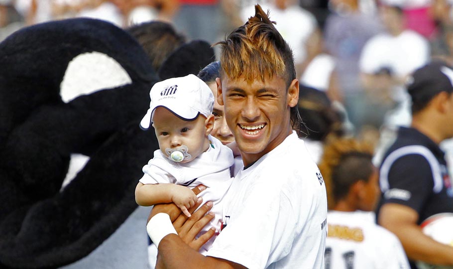 Neymar smiling as he holds his baby son David Lucca, in Santos