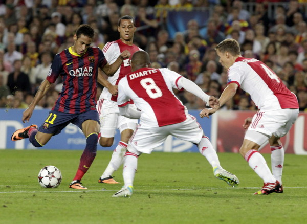 Neymar trying to shoot the ball between the legs of two Ajax defenders
