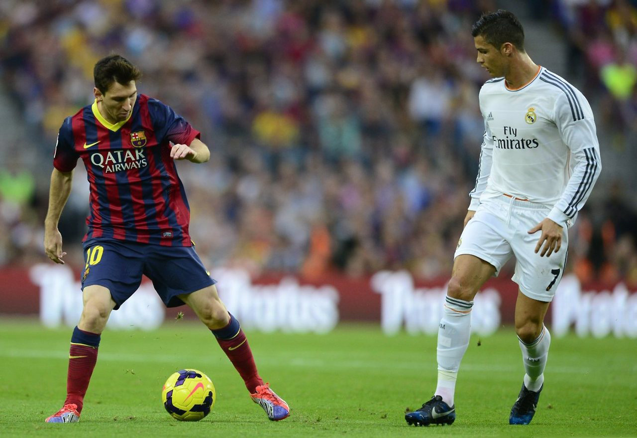 Lionel Messi holding to the ball, with Cristiano Ronaldo observing