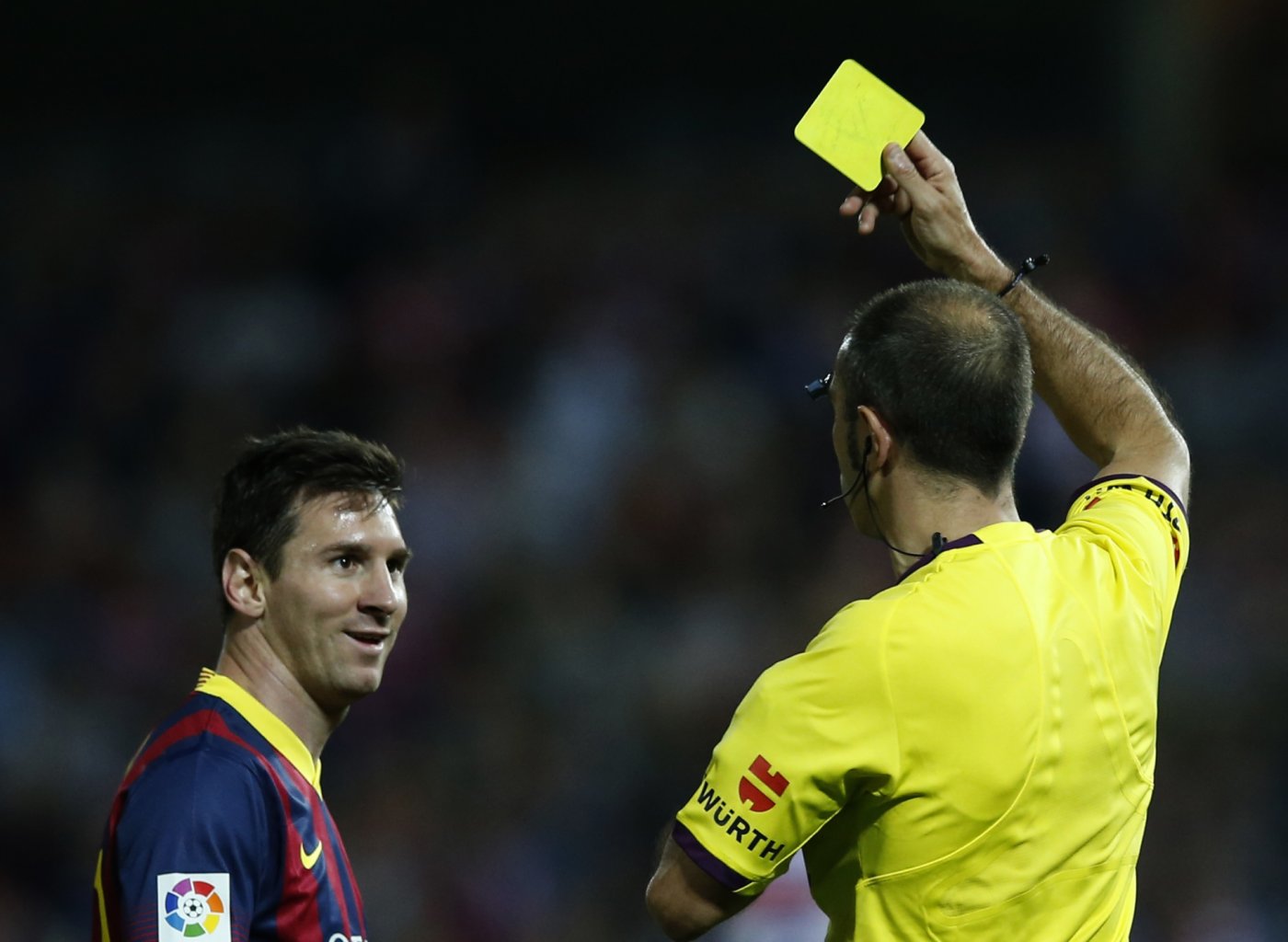 Messi being shown the yellow card and reacting with a smile